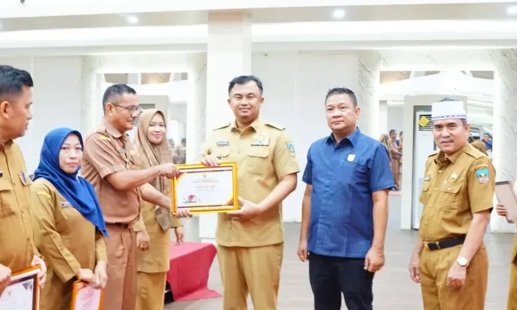 Bupati Dharmasraya, Sutan Riska Tuanku Kerajaan menyerahkan piagam penghargaan pengawasan kearsipan internal Pemkab Dharmasraya tahun 2024 di Auditorium Kantor Bupati, Senin, (30/12).