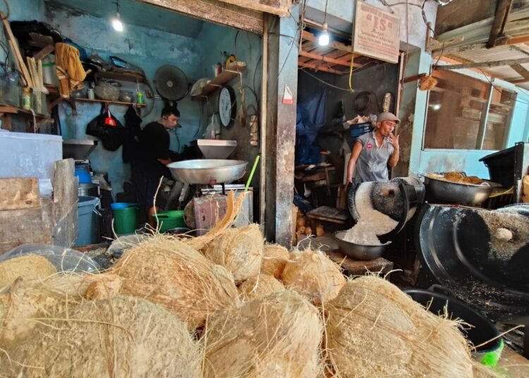 Rendi, Pedagang Santan di Pasar Raya Padang, memproduksi santan kelapa di kedainya, Kamis (10/4). Foto: Habil Ramanda