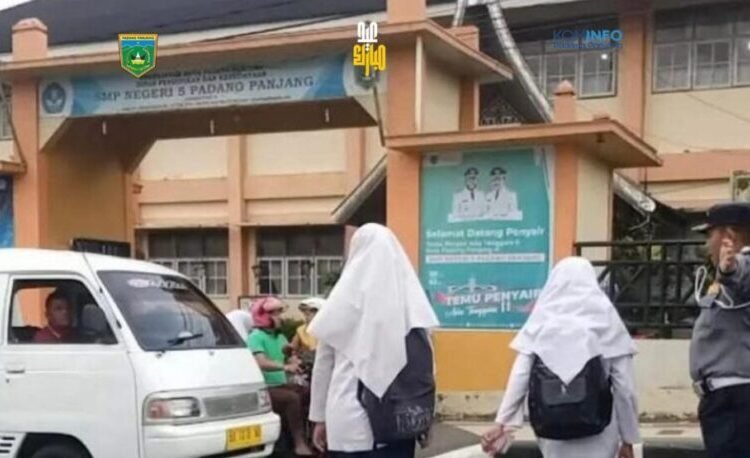 Petugas mengatur lalu lintas saat pelajar hendak memasuki area sekolah di Padang Panjang. Foto: Ist