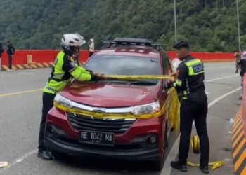 Polisi Pasang Garis Polisi pada Kendaraan Parkir di Jembatan Kelok 9
