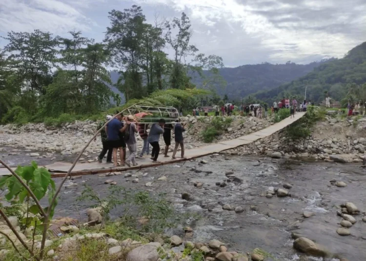 Sejumlah warga menggotong keranda berisi jenazah warga yang terjatuh ke sungai dari jembatan darurat di Nagari Koto Rawang, Kecamatan IV Jurai, Pesisir Selatan, pada Minggu (20/7) siang. Foto: IST