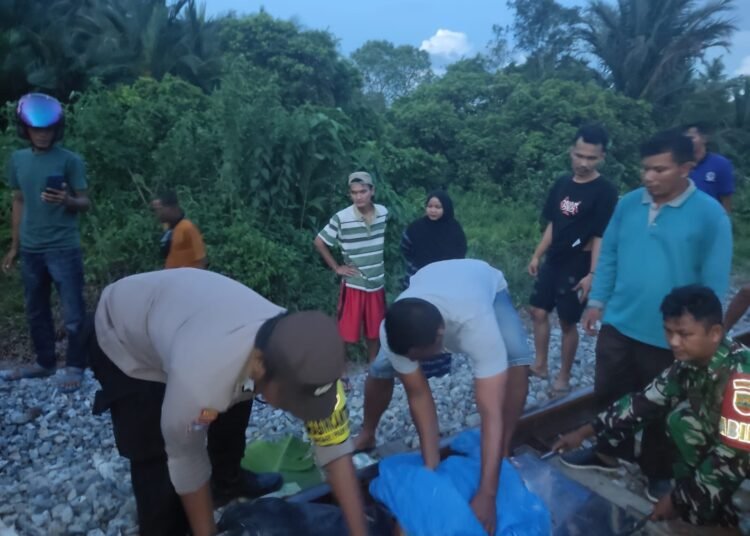 Polisi, tentara, dan warga mengevakuasi jenazah seorang wanita yang ditabrak kereta api di Korong Pagua Duku, Nagari Kurai Taji, Kecamatan Nan Sabaris, Padang Pariaman, Sabtu (12/7/2025) sore.