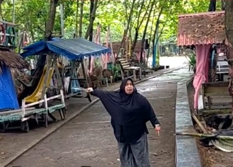 Seorang emak-emak, pedagang di Pantai Anas Malik, membawa golok dan memaki-maki petugas untuk menolak pembangunan radar tsunami di pantai itu pada Senin (14/7). Foto: IST