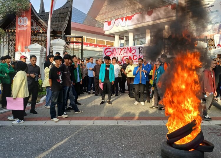 Mahasiswa membakar ban saat berdemonstasi di depan Kantor DPRD Sumbar pada Senin (4/8). Foto: Dharma Harisa