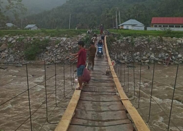 Warga Nagari Koto Rawang, Kecamatan IV Jurai, Pesisir Selatan, memperbaiki jembatan darurat di nagari itu baru-baru ini. Seorang warga meninggal setelah terjatuh dari jembatan itu pada Minggu (20/7). Foto: Aji Pessel