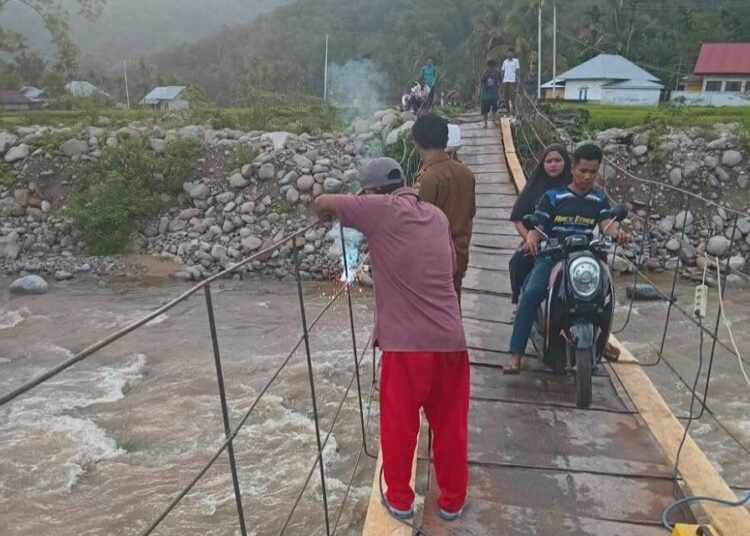Warga Nagari Koto Rawang, Kecamatan IV Jurai, Pesisir Selatan, memperbaiki jembatan darurat di nagari itu baru-baru ini. Seorang warga meninggal setelah terjatuh dari jembatan itu pada Minggu (20/7). Foto: Aji Pessel