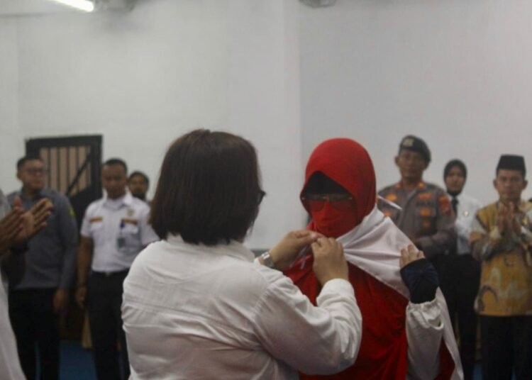 Kepala Lapas Perempuan Kelas IIB Padang, Susi Andriany Pohan, memasangkan bendara merah putih kepada narapidana perempuan kasus terorisme di lapas itu pada pada Kamis (21/8) dalam ikrar setia kepada NKRI. Foto: Lapas Perempuan Kelas IIB Padang
