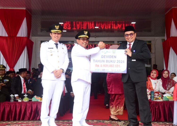 Kepala Bank Nagari Cabang Lubuk Alung, Afrizon menyerahkan deviden kepada Bupati Padang Pariaman, John Kenedy Azis, usai upacara peringatan HUT berlangsung di halaman kantor bupati, Minggu (17/8/2025).