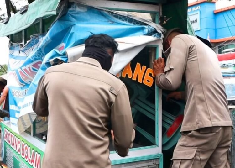 Satpol PP melakukan penertiban terhadap PKL yang menggunakan badan jalan di kawasan Pasar Bandar Buat, Lubuk Kilangan, Sabtu (06/9/2025).