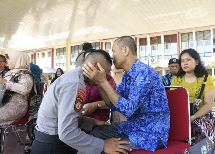 Railin Zai mencium kepala putranya, Bripda Bortolomeus Viktor Zai, usai dilantik sebagai anggota Polri di SPN Polda Sumatera Barat, Rabu (24/12/2025). Foto: Tribratanews Polda Sumbar