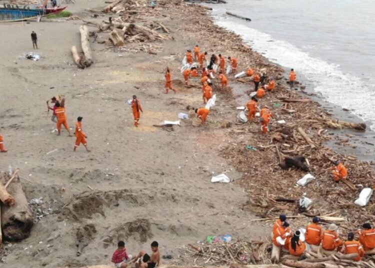 Petugas Dinas Lingkungan Hidup (DLH) Kota Padang sedang membersihkan sampah yang menumpuk terbawa banjir bandang.