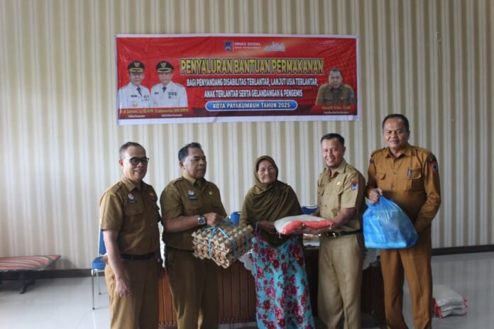 Staf Ahli Bidang Kemasyarakatan dan SDM bersama Kepala Dinas Sosial Payakumbuh menyerahkan bantuan permakanan kepada penerima manfaat di Aula Dinsos, Selasa (9/12/2025).