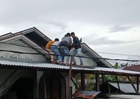 Warga menurunkan seorang pria yang tersetrum di atap rumah warga di jalan ke Perumahan Garden, Jorong Katimaha Utara, Nagari Lingkung Aur Koto Dalam, Kecamatan Pasaman, Pasaman Barat, pada Sabtu (13/12) siang.