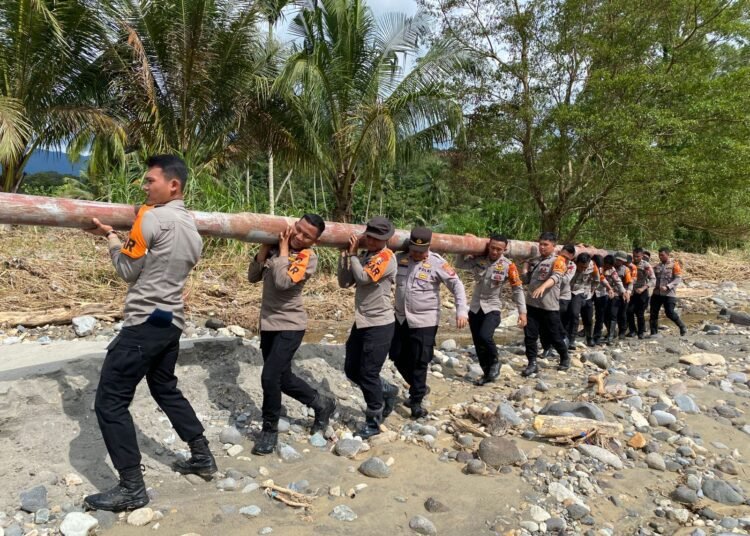 Polisi dan Brimob mengangkat tiang listrik ke lokasi yang putus total akibat banjir dan longsor di Kayu Tanam Padang Pariaman, Kamis (4/12/2025).