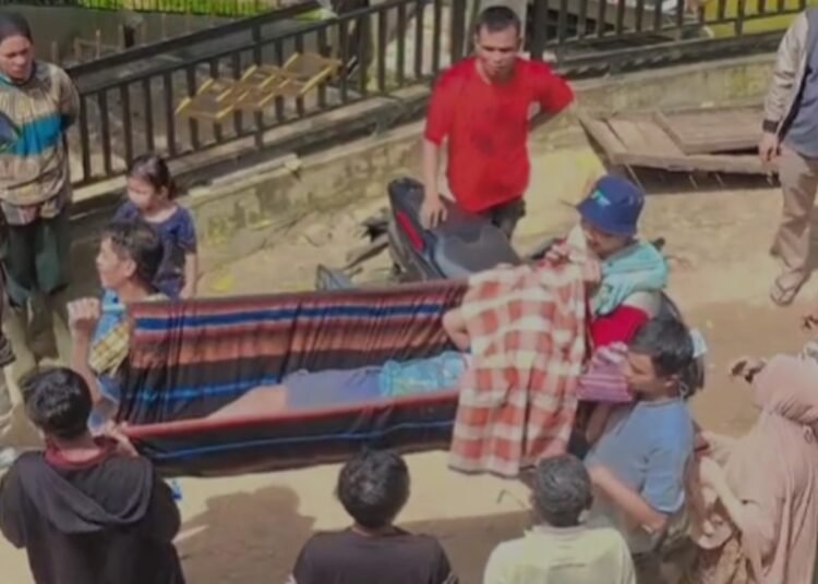 Warga Kampung Ngalau Gadang, Nagari Limau Gadang, Kecamatan Bayang Utara IV Nagari, Pesisir Selatan, gotong royong menandu seorang anak berusia 11 tahun, Aras, menuju titik yang bisa dilalui kendaraan, pada Rabu (21/1/2026). Foto: Ist