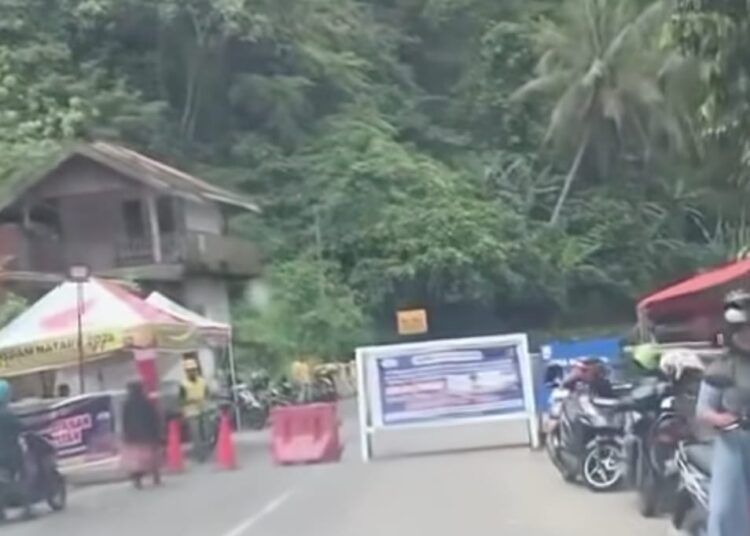 Tangkapan layar video yang beredar di media sosial memperlihatkan sebuah mobil melintas setelah portal jalur Padang–Bukittinggi via Lembah Anai dibuka oleh pria berompi kuning, Senin (23/2/2026). Dalam narasi video, disebutkan kendaraan dapat melintas di luar jam operasional dengan membayar sejumlah uang.