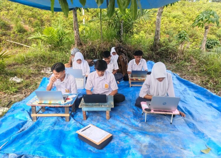 Sejumlah siswa SMPN 4 Kapur IX mengikuti Ujian Tes Kemampuan Akademik (TKA) di perbukitan Batu Sampik, Limapuluh Kota, dengan fasilitas seadanya demi mendapatkan jaringan internet.