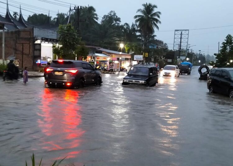 Jalan lintas Padang—Pasaman Barat Kilometer 117 terendam banjir setinggi 40 hingga 50 sentimeter akibat hujan deras di depan Balerong Adat Nagari Bawan, Jorong Koto Padang, Kecamatan Ampek Nagari, Agam, pada Minggu (14/6/2026) sore. Foto: BPBD Agam