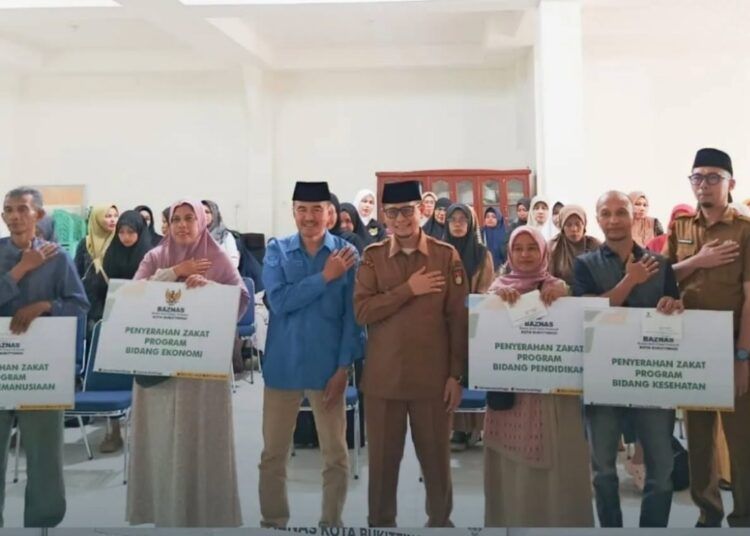 Wakil Wali Kota Bukittinggi Ibnu Asis bersama jajaran Baznas Kota Bukittinggi menyerahkan bantuan zakat dan infak kepada mustahik di Aula Kantor Baznas Bukittinggi, Selasa (7/7/2026).