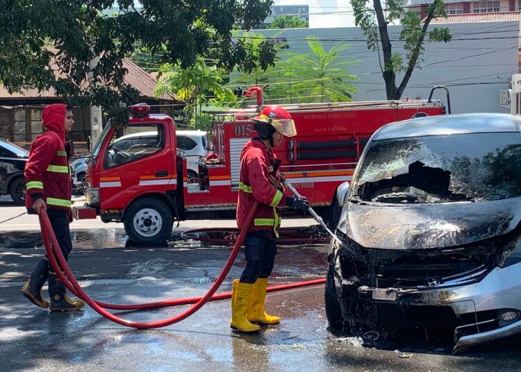 Petugas Damkar Kota Padang memadamkan api yang menghanguskan sebuah mobil Honda Freed di depan McDonald's Ahmad Yani, Padang, Jumat (24/7/2026).