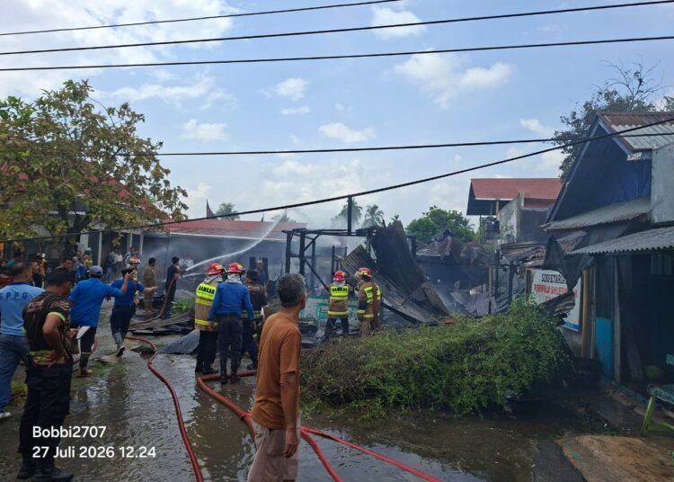 Petugas pemadam kebakaran berjibaku memadamkan api yang menghanguskan sebuah kedai fotokopi dan merusak kedai makan di Jalan Perkompleksan Pemda Kota Solok, Senin (27/7/2026).