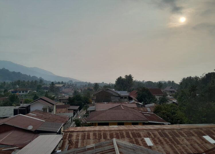 Kabut asap tampak menyelimuti kawasan permukiman di Kota Padang, Senin (24/8/2026), membuat sinar matahari terlihat redup di tengah kondisi udara yang berkabut.