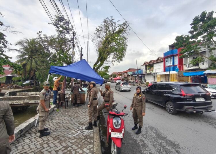 Satuan Polisi Pamong Praja (Satpol PP) Padang membongkar sejumlah lapak Pedagang Kaki Lima (PKL) yang ditinggalkan pemilik usai berjualan di atas trotoar kawasan Pasar Alai, tepatnya di depan Puskesmas Alai, Kecamatan Padang Utara, pada Senin (3/8/2026). Foto: Satpol PP Padang