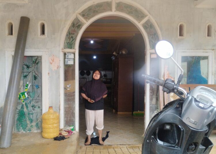 Ina Lusiana membersihkan lumpur yang masih menggenangi rumahnya di Kelurahan Tabiang Banda Gadang, Kecamatan Nanggalo, Kota Padang, Rabu (5/8/2026).