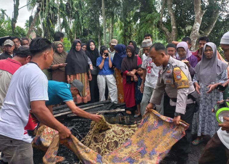 Puluhan warga menyaksikan polisi mengevakuasi jenazah korban kebakaran di rumah pondok kayu berukuran 4x4 meter di ladang di Kampung Koto Rawang, Nagari Lakitan Timur, Kecamatan Lengayang, Pesisir Selatan, Sumatera Barat (Sumbar), pada Kamis (6/8/2026) pukul 4.00 WIB. Foto: Polsek Lengayang