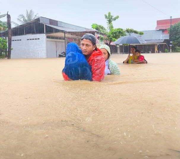 Sejumlah warga melintasi genangan banjir di kawasan terdampak di Kota Padang, Senin (3/8).