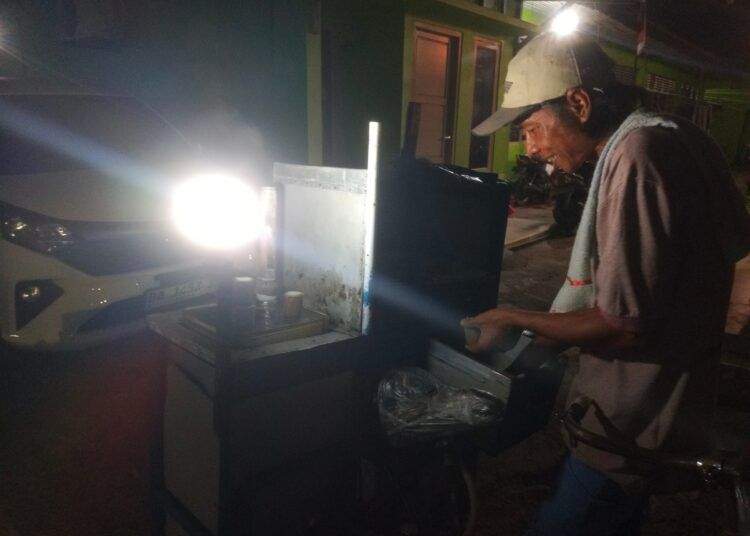 Abdul alias Syukur (42) berjualan putu menggunakan sepeda gerobaknya di Kota Padang, Sumatera Barat, Kamis (27/8/2026) malam.