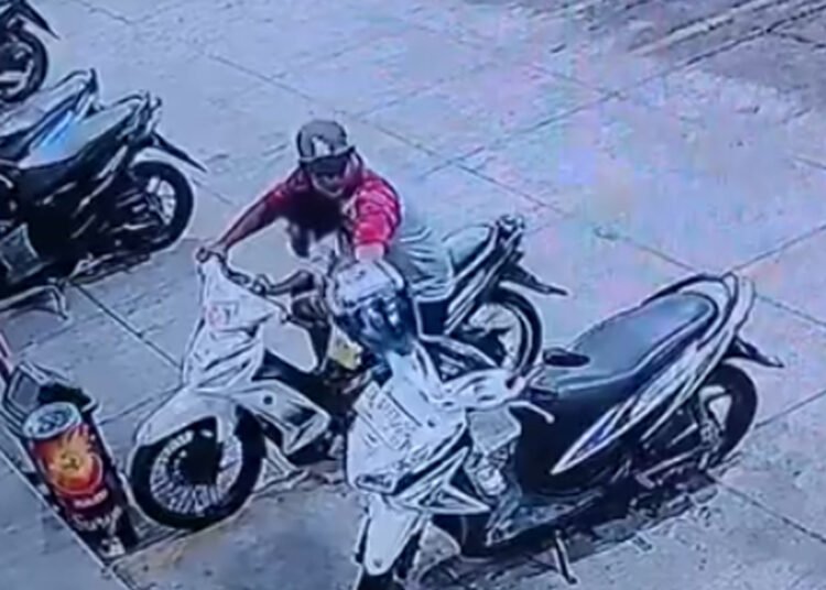 Rekaman CCTV memperlihatkan seorang pria yang membonceng anak saat diduga mengambil helm dari sepeda motor di depan Mini Market Ayang Denai, Kampung Baru, Kota Pariaman.