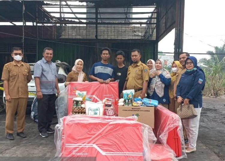 Pelaksana Tugas (Plt.) Kepala Dinas Sosial Pemberdayaan Perempuan, Perlindungan Anak, Pengendalian Penduduk dan Keluarga Berencana Kabupaten Dharmasraya, Helmy Muslim beserta jajaran menyalurkan bantuan kebutuhan dasar kepada korban kebakaran di Nagari Sungai Rumbai Timur, Kecamatan Sungai Rumbai, Selasa (6/10/2026).