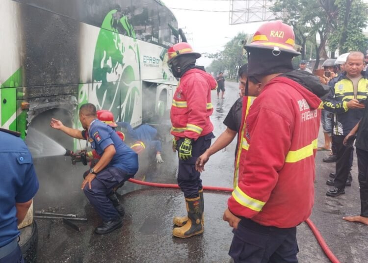 Petugas memadamkan api yang membakar sebuah bus pariwisata rute Palembang–Padang di kawasan Bandar Buat, Kecamatan Lubuk Kilangan, Kota Padang, Sumatera Barat, pada Selasa (13/10/2026) pagi.