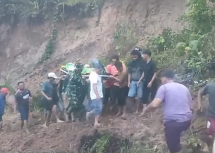 Sejumlah warga berjibaku membawa jenazah melewati jalan yang tertutup material longsor di Labuah Sampik, Jorong Ngungun, Nagari Salareh Aia, Kecamatan Palembayan, Kabupaten Agam, Sumatera Barat, pada Minggu (18/10/2026) sore. Foto: Tangkapan layar media sosial