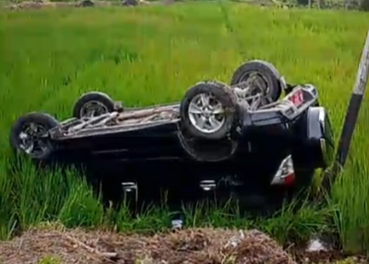 Minibus berwarna hitam terbalik di area persawahan di Jorong Gaduang Dama, Nagari Cupak, Kecamatan Gunung Talang, Kabupaten Solok, Senin (26/10/2026).