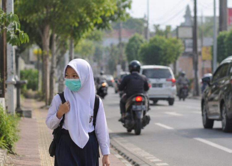 Ilustrasi seseorang sedang memakai masker saat berada di jalan. Foto ilustrasi AI